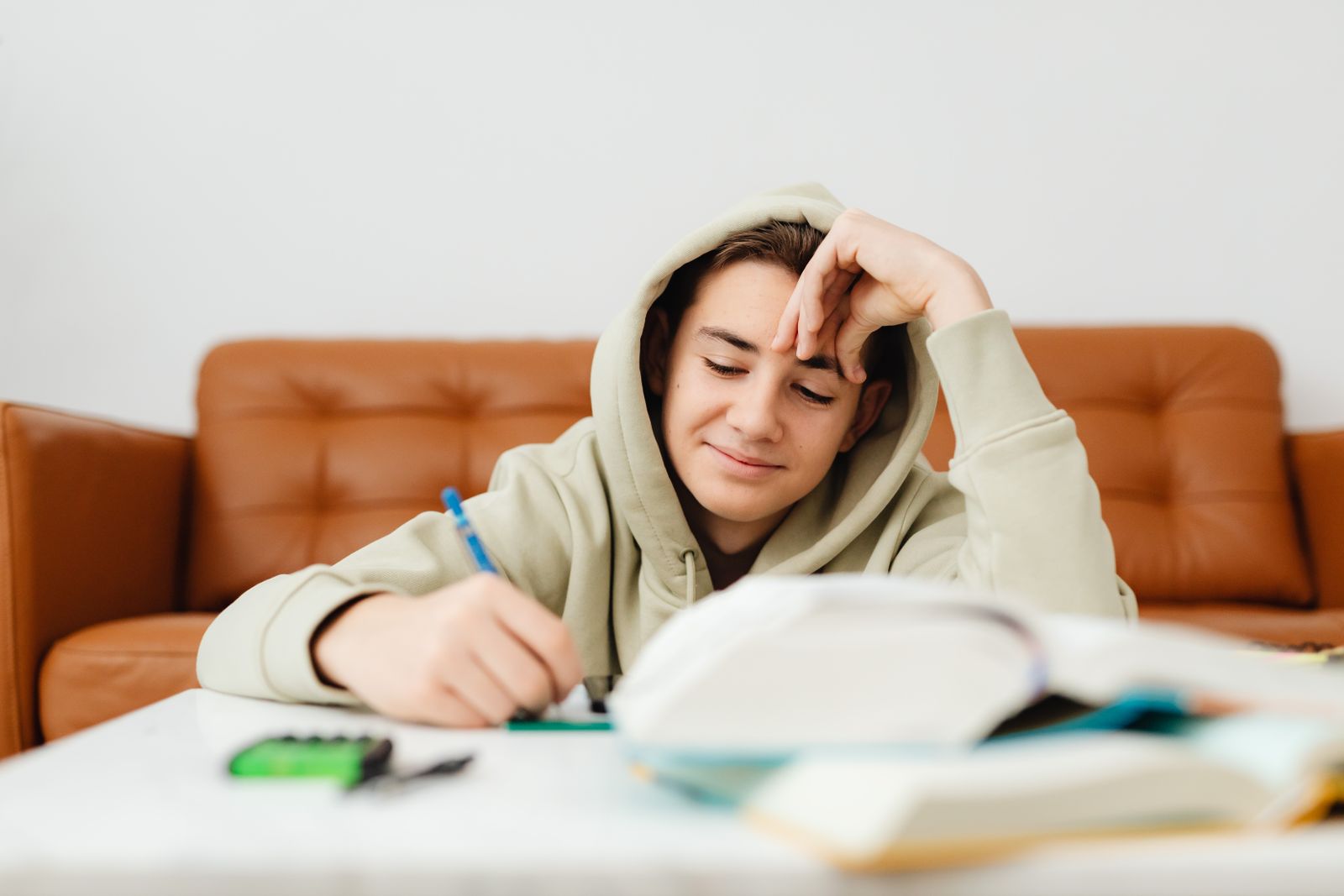 Un adolescente estudia en su casa con apuntes sobre la mesa
