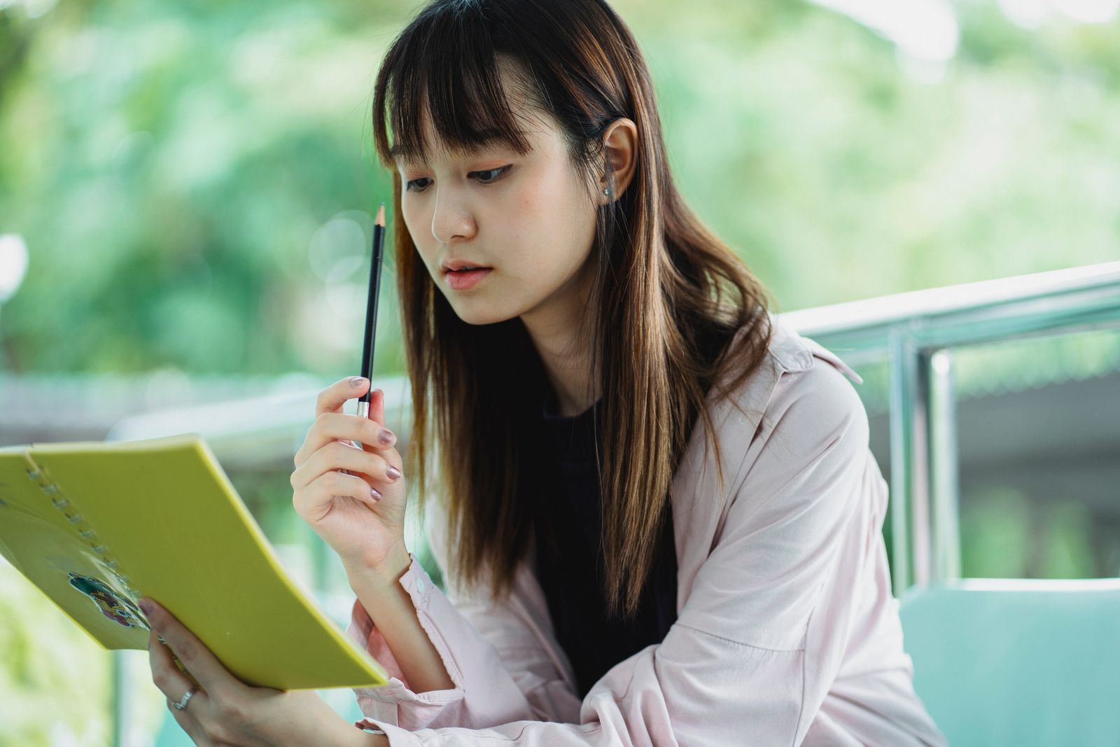 Una estudiante concentrada lee su cuaderno con un lápiz en la mano